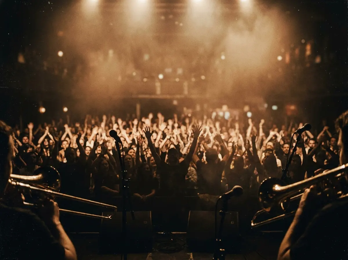 Audience hands raised in warm stage light